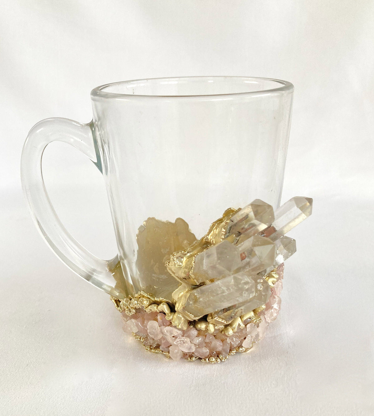 Clear glass mug with decorative elements including gold leaf and crystals on a white background